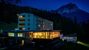 A multi-story hotel with balconies, a glass facade, and a mountain backdrop. - Hotel Boboty (Terchova)