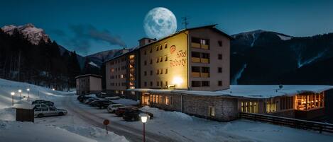 A hotel with a large sign reading "hotel Boboty" in a snowy mountainous area at night.
