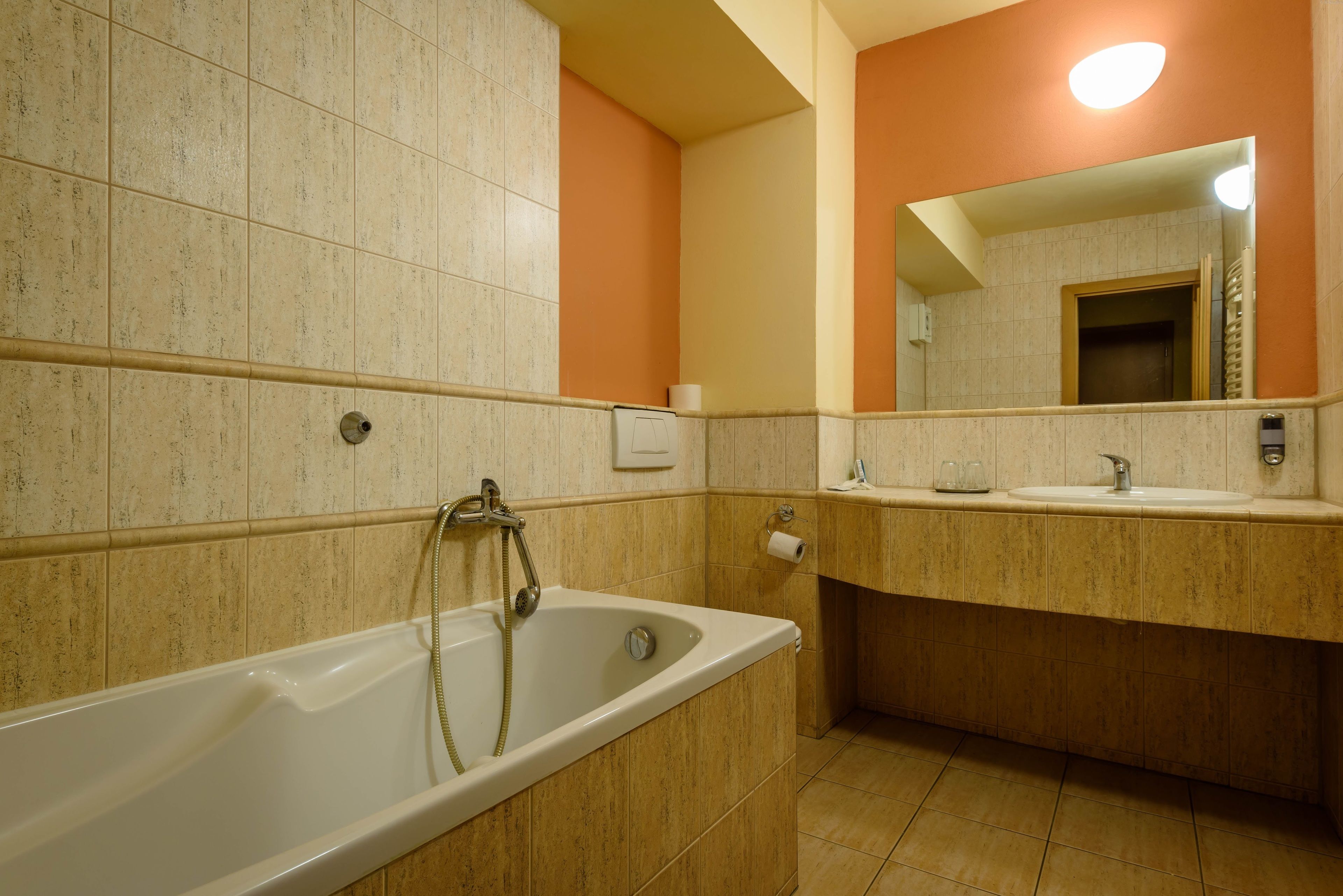 Un baño con bañera, lavamanos y espejo.