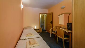 A hotel room with two beds, a desk with a chair, a television, and a door leading to another room.