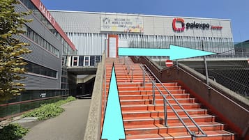 A building with a sign reading "Welcome to the World of Coffee Geneva" and "Palexpo Centre" with a staircase leading up to it.