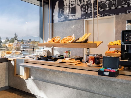 A breakfast buffet with bread, pastries, and fruit.. ibis budget Genève Palexpo Aéroport
