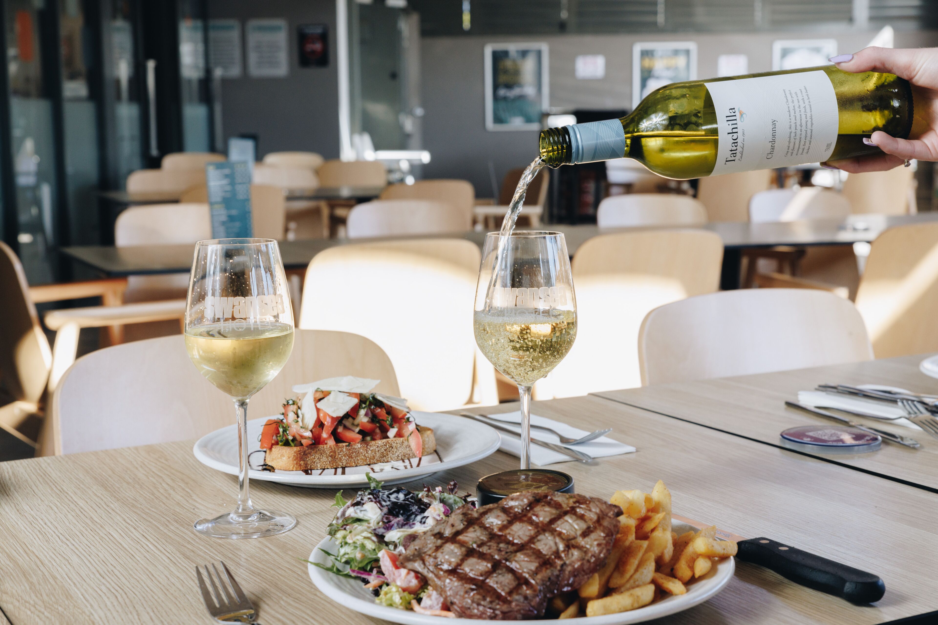 Ein Restaurant mit einem Tisch für zwei Personen, serviert mit einem Steak, Pommes und einem Salat.