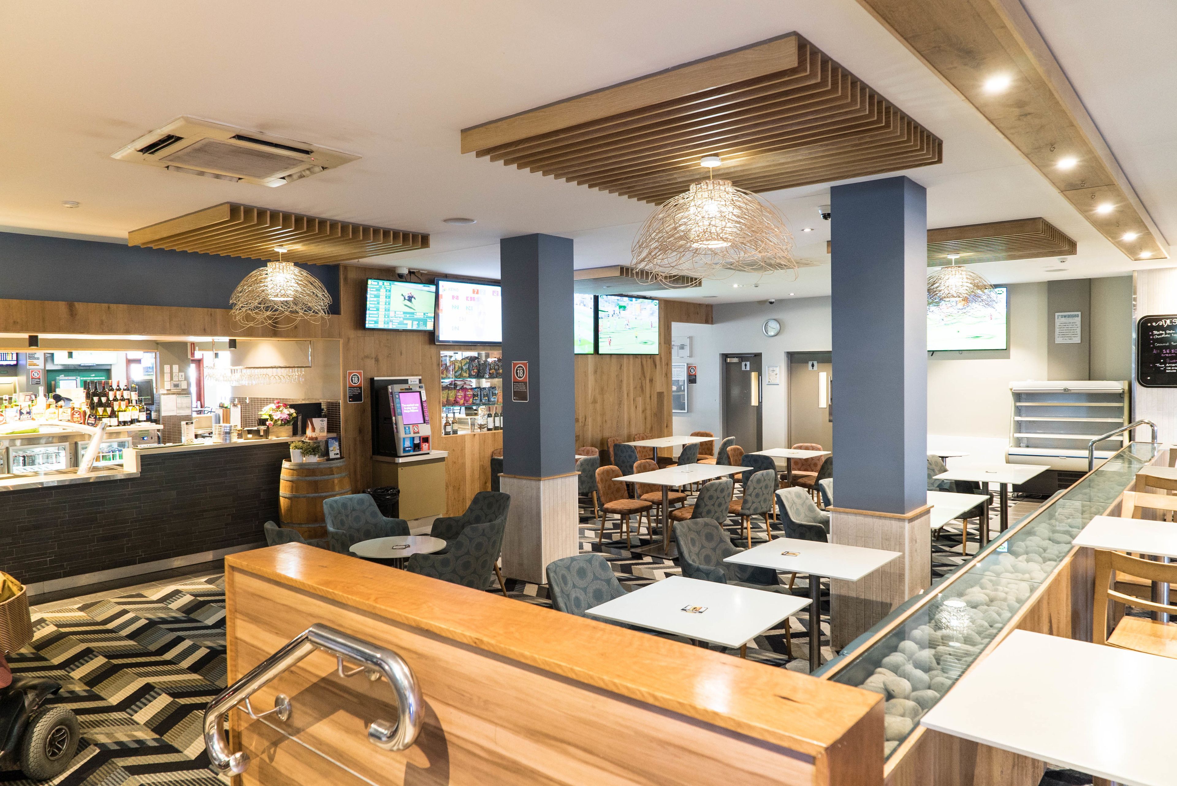Un restaurante moderno con zona de bar, distribuciones de asientos y un diseño de techo singular.
