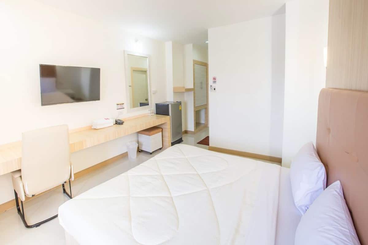 A hotel room with a bed, a desk, a chair, a television, and a mirror.
