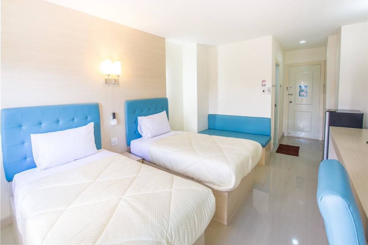 A hotel room with two beds, a desk, and a seating area.