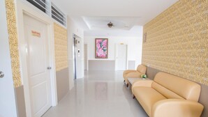 A hotel corridor with a sofa, doors, and patterned wallpaper. - P.A. Thani Hotel (Nakhon Sawan)