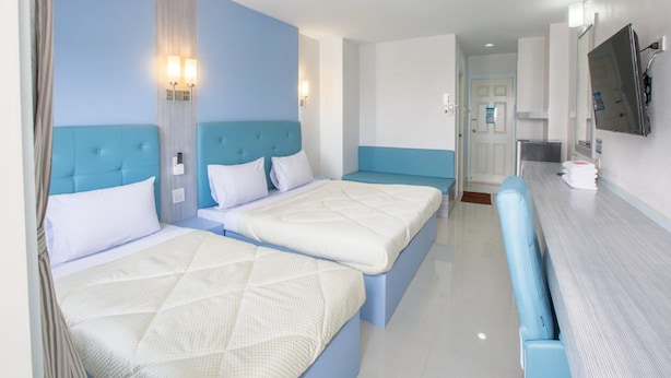 A hotel room with two beds, a small seating area, a TV, and a bathroom visible through an open door. - P.A. Thani Hotel (Nakhon Sawan)