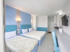 A hotel room with two beds, a small seating area, a TV, and a bathroom visible through an open door. - P.A. Thani Hotel (Nakhon Sawan)