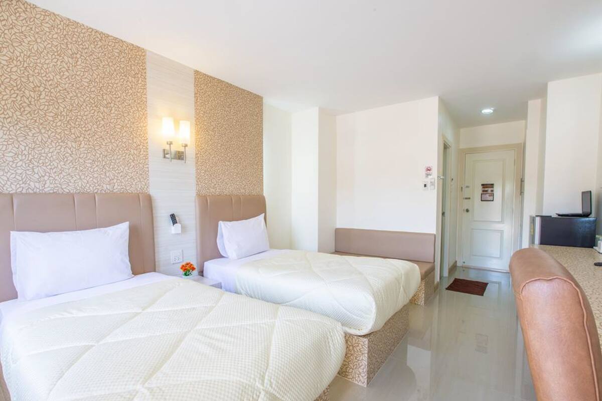 A hotel room with two beds, a sofa, a TV, and a wall with a textured pattern.
