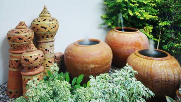 The exterior of P.A. Place Hotel with a sign in Thai and English, large clay pots, and potted plants. - P.A. Place Hotel (Nakhon Sawan)
