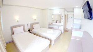 A hotel room with two beds, a small desk, a mirror, and a TV. - P.A. Place Hotel (Nakhon Sawan)