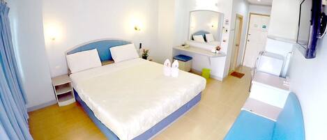 A hotel room with a large bed, a desk, a mirror, and a TV.