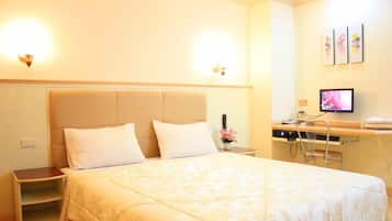 A hotel room with a bed, bedside tables, a desk with a computer, and wall-mounted artwork.
