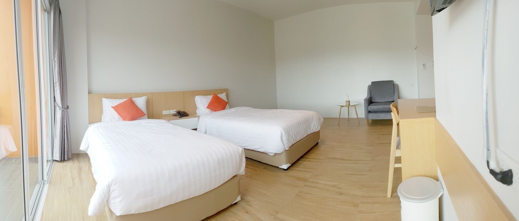 Habitación de hotel con dos camas, un escritorio pequeño, una silla y un cubo de basura.