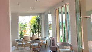 A modern interior with a long, reflective floor, a seating area with chairs and a table, and large windows allowing natural light. - Sleeping Tree Hotel (Fang)