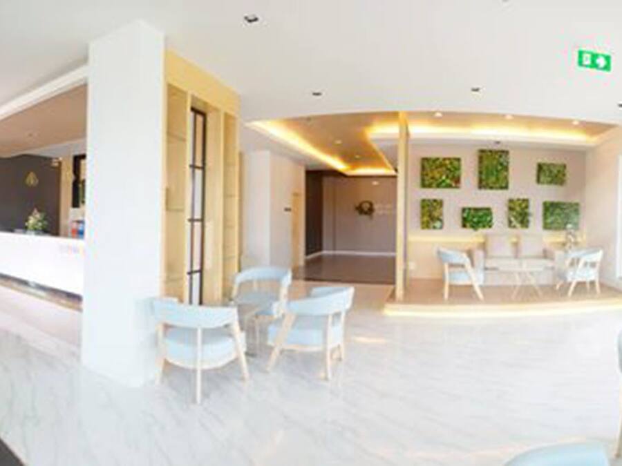 A spacious lobby with a reception desk, seating area, and a wall with patterned tiles.