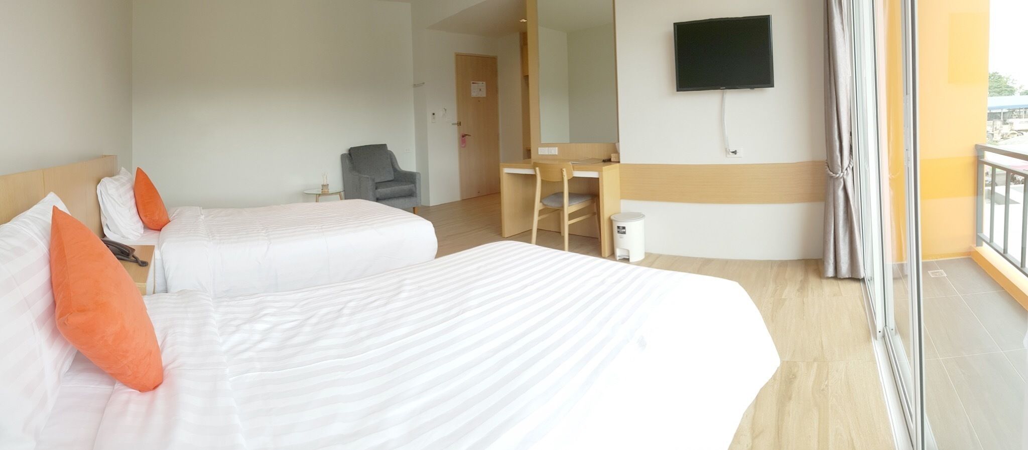 Habitació d'hotel amb dos llits, una taula, una cadira, una televisió i un balcó amb vistes.