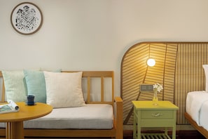 Una habitación con cabecera de madera, una mesita de noche pequeña con una lámpara, y una cama con ropa blanca.