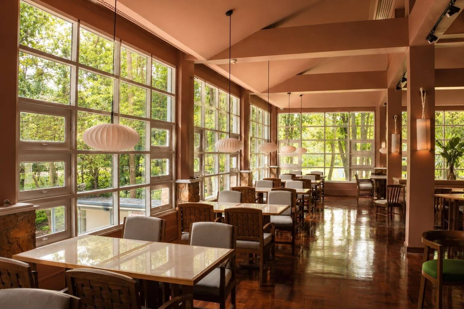 A spacious dining area with large windows, wooden tables, and chairs.