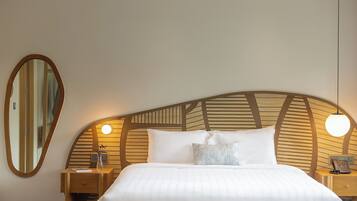Una cama bien hecha con cabecera de madera, dos mesitas de noche con lámparas y un espejo grande en la pared.