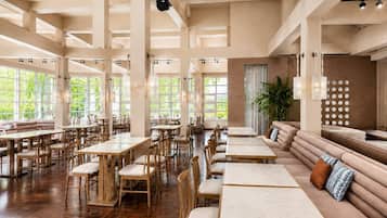 A spacious restaurant with high ceilings, large windows, and a mix of wooden tables and seating areas.