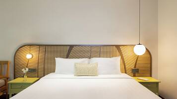 A neatly made bed with a patterned headboard, bedside tables with lamps, and a simple chair.