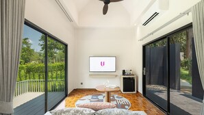 Una sala moderna con ventilador de techo, televisor, una mesita con alfombra y un sofá con cojines.