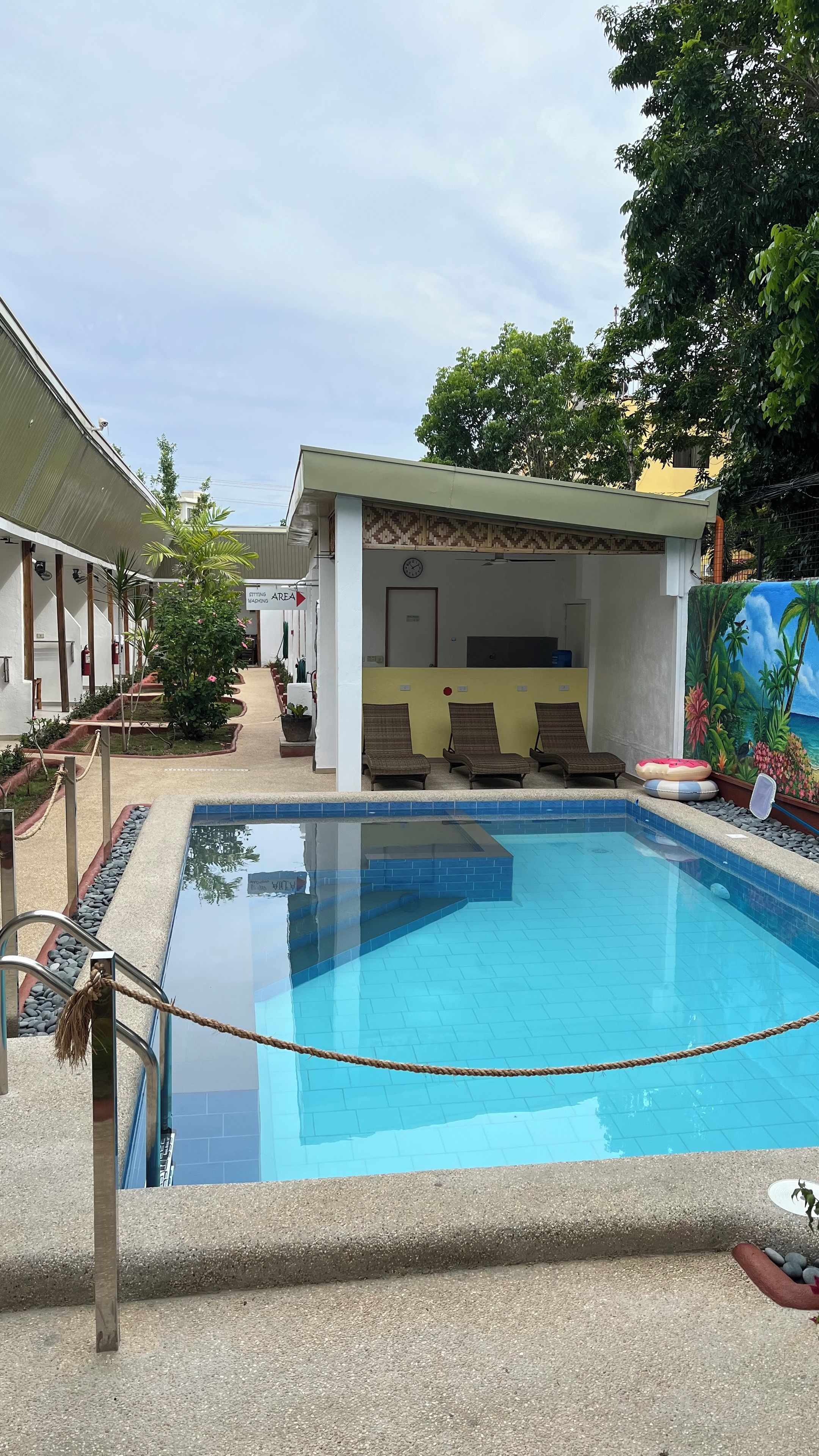 Una piscina con sillones de descanso y una zona de estar cubierta.
