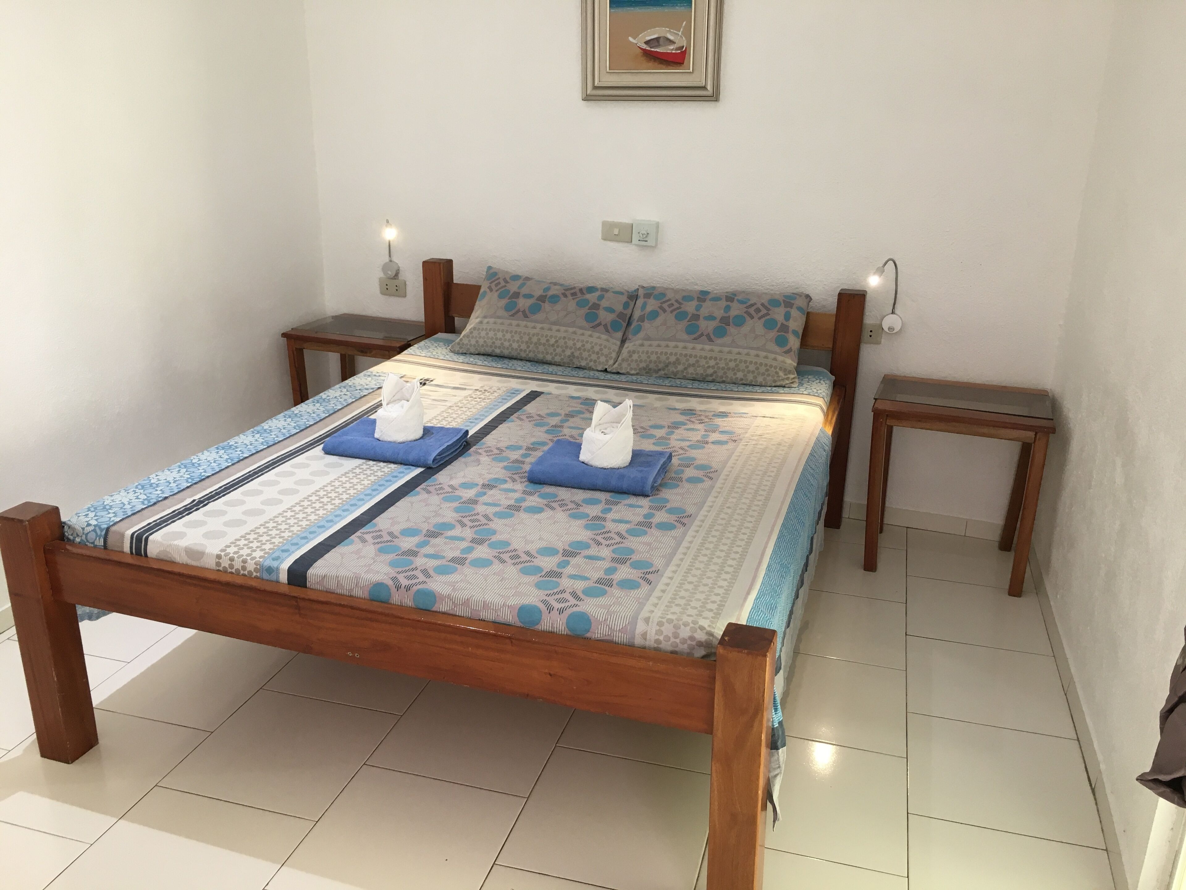 A neatly made bed with a patterned bedspread, two pillows, and two folded towels.