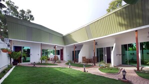 A modern building with a covered patio area, outdoor seating, and a well-maintained lawn. - Alona Gecko Inn (Panglao)
