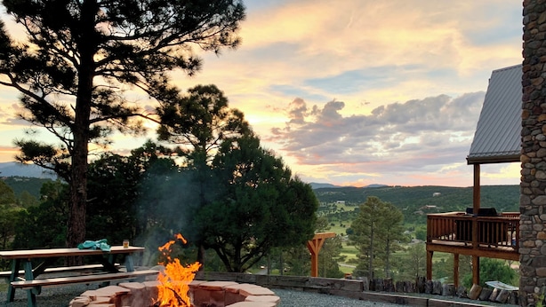 A stone fire pit with a view of a mountainous landscape and a wooden deck.