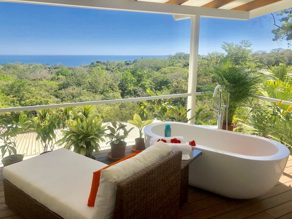 A balcony with a white bathtub, wicker furniture, and potted plants. - Chez Mu Luxury Villa - Amazing Ocean & Jungle Views 1 Mi/TownNew Pictures!!! (Montezuma)