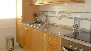 A kitchen with wooden cabinets, a granite countertop, stainless steel appliances, and a dish rack. - Confortable T1 in promenade of the sea and beach, sea view, Armação Pêra Algarve (Armação de Pêra)