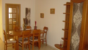 A dining area with a wooden table and chairs, a bookshelf, and a door with glass panels. - Confortable T1 in promenade of the sea and beach, sea view, Armação Pêra Algarve (Armação de Pêra)