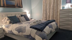 A neatly made bed with a leaf-patterned duvet, a bedside lamp, and a nightstand with a lamp. - Steps to US Capitol - US Supreme Court and Monuments (Washington)