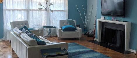 Un salon avec un canapé, des fauteuils, une cheminée et un téléviseur.