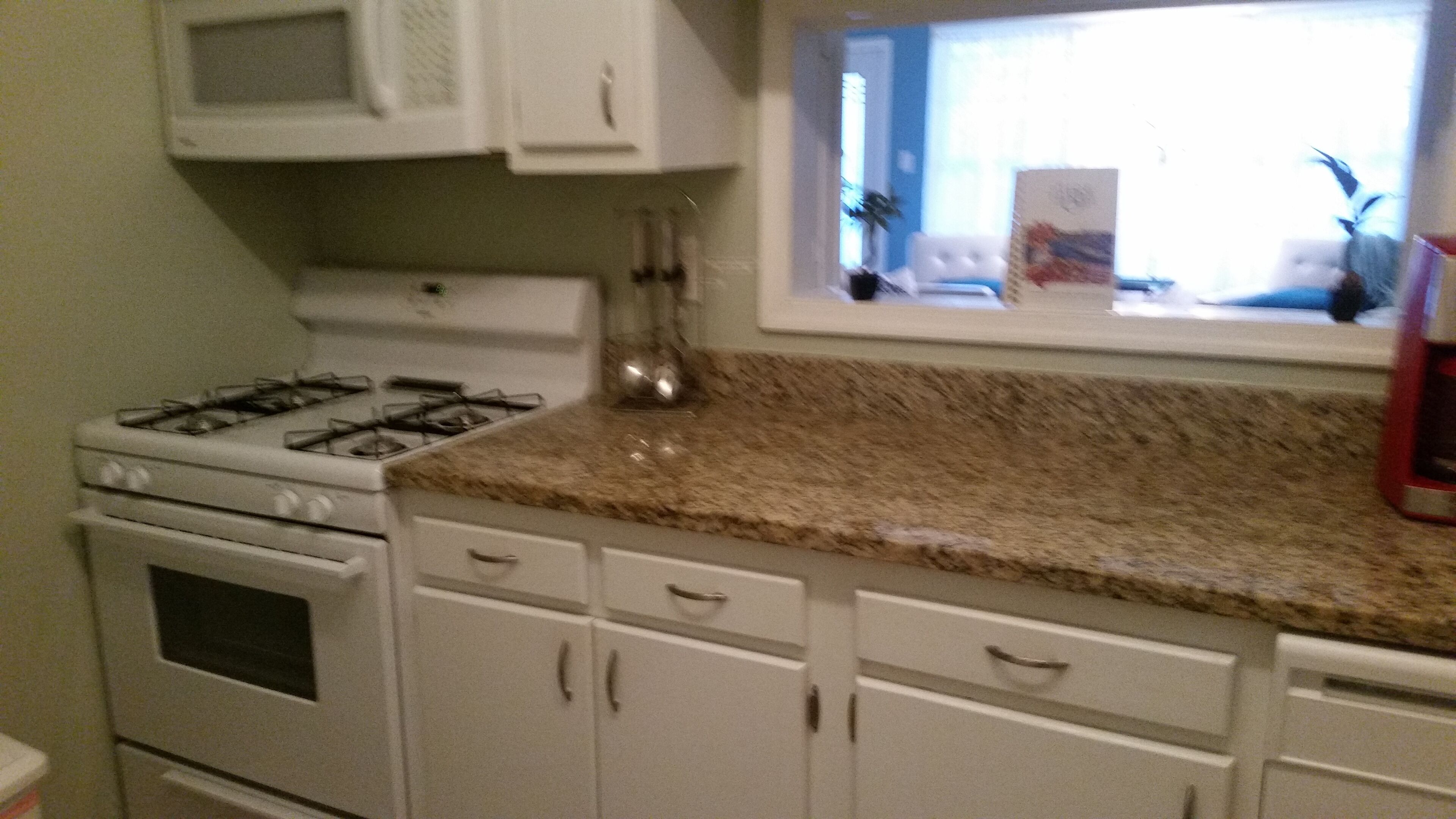 A kitchen with white cabinets, a gas stove, and a microwave.