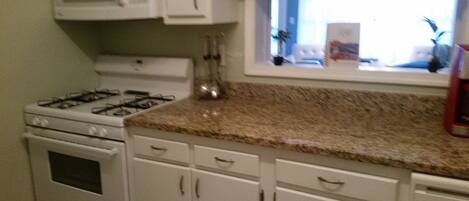 A kitchen with white cabinets, a gas stove, and a microwave.