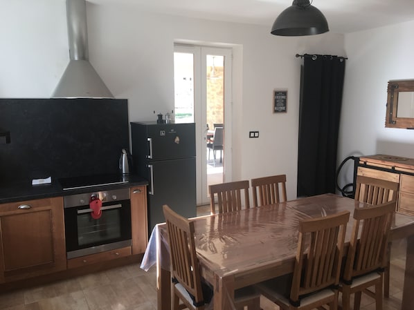 Une cuisine équipée d’une cuisinière, d’un four, d’un réfrigérateur et d’une table à manger avec des chaises.