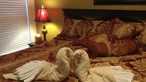 Ein Bett mit einer roten und goldenen Tagesdecke, eine rote Lampe und eine Wand mit einem Gemälde.