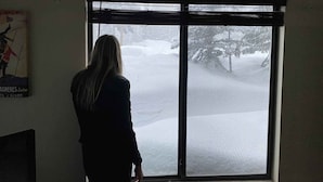 Una persona in piedi vicino a una finestra con vista su un paesaggio innevato.