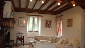 Ein gemütliches Zimmer mit Bett, Sessel, Tisch und Fenster.