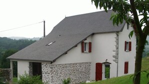 Ein zweistöckiges Haus mit Steinunterbau und grauem Dach.