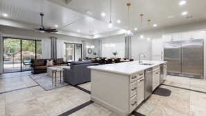 A spacious kitchen with a central island, a dining area, and a living room with a sofa and coffee table.