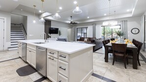 A spacious kitchen with a central island, modern pendant lighting, and a dining area with a large table and chairs.