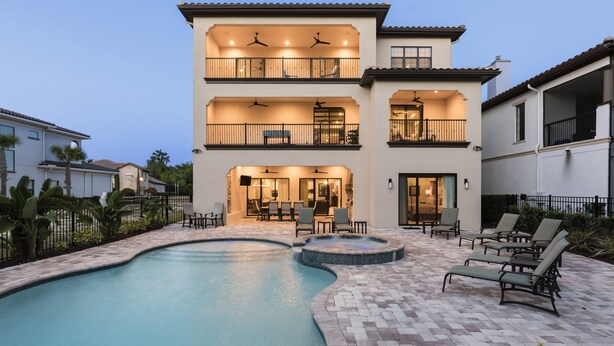 A two-story house with a swimming pool, outdoor seating, and a patio area.
