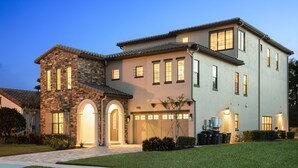 A two-story house with a stone facade, a large garage, and a well-maintained lawn.