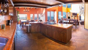 Uma cozinha espaçosa com uma ilha grande, piso de pedra e armários de madeira.