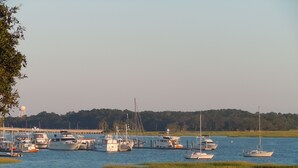 En småbåtshamn med flera båtar förtöjda, omgiven av vatten och grönområden.